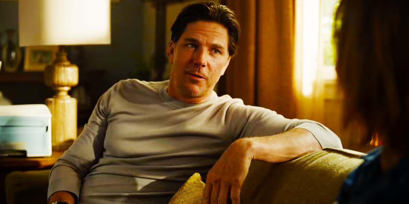 Michael Trucco as Luke Leone sitting on his couch and speaking to someone in Fire Country season 1, episode 8