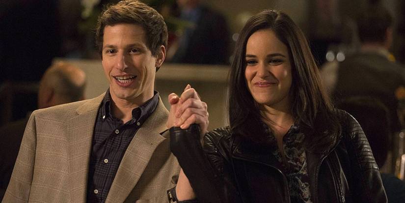 Jake (Andy Samberg) e Amy (Melissa Fumero) de mãos dadas em Brooklyn Nine-Nine
