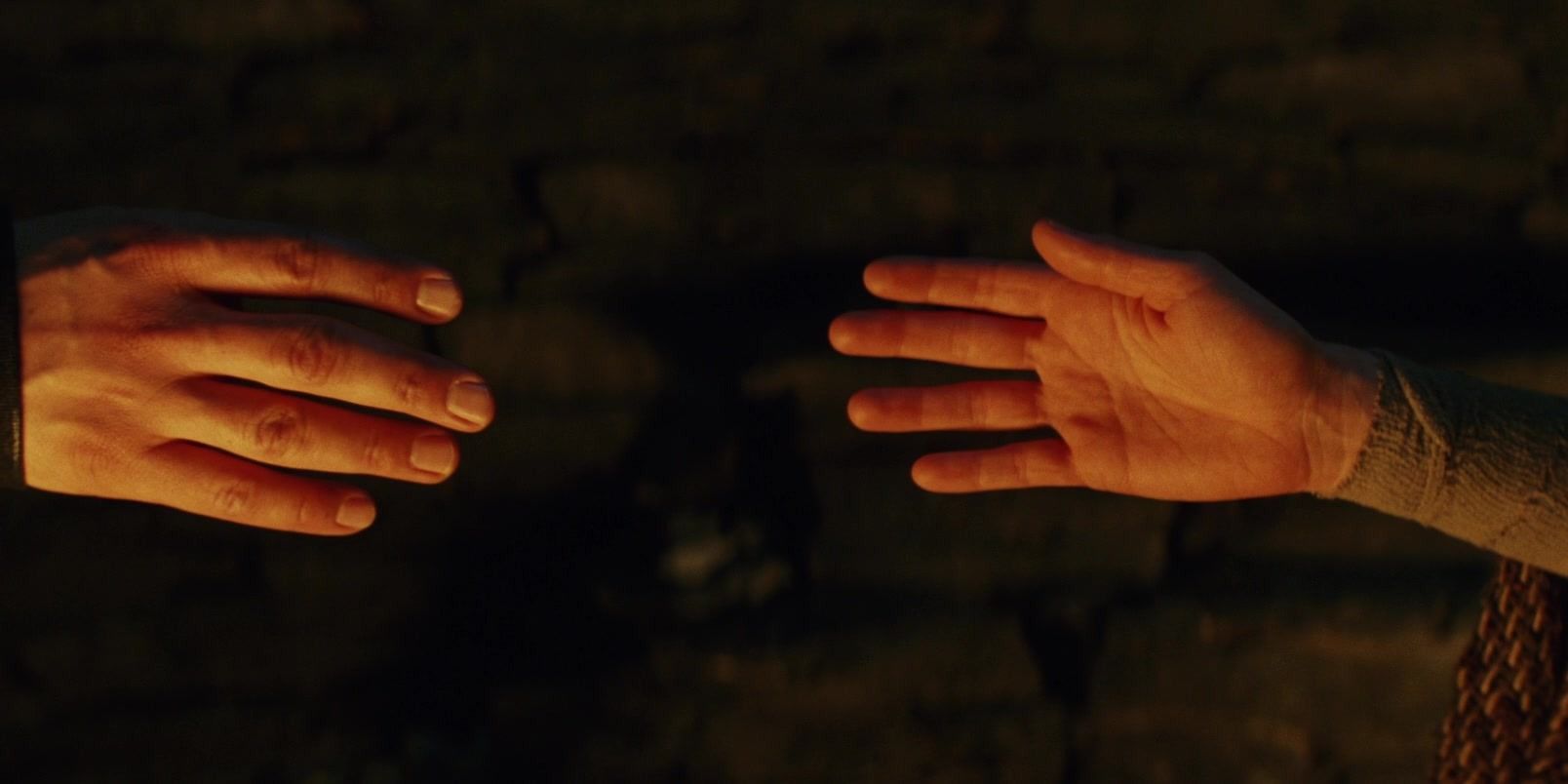 Rey and Kylo Ren's hands reaching toward one another in The Last Jedi