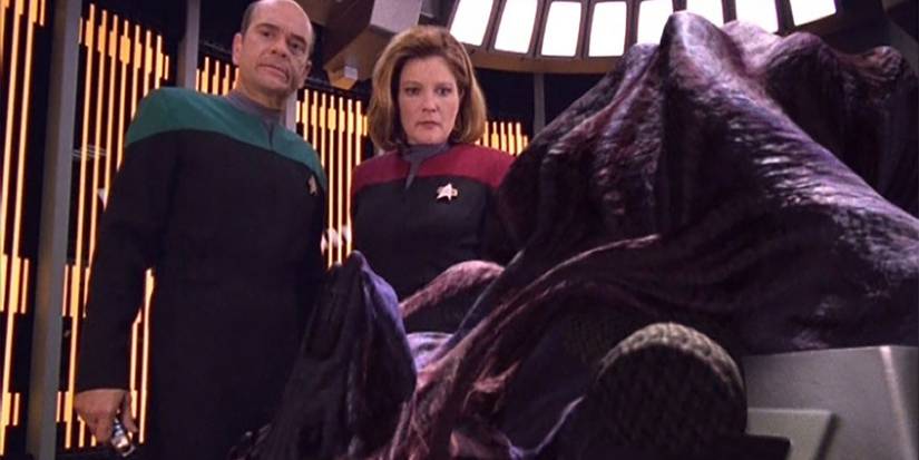 The Doctor and Janeway look down at a Species 8472 in Voyager's medbay biobed Voyager In the Flesh
