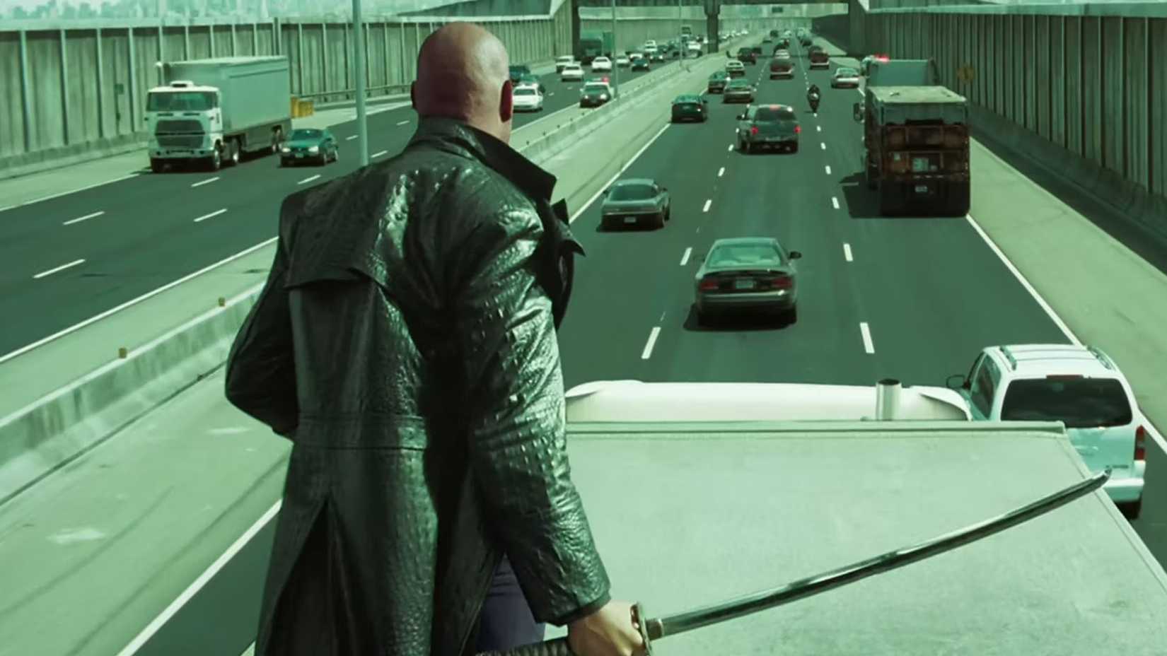 Morpheus segurando uma espada enquanto está em um caminhão em movimento na rodovia em Matrix Reloaded