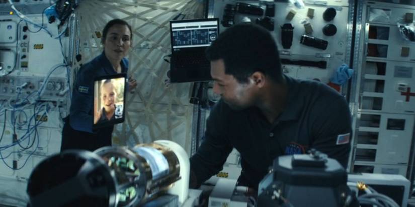 Номи Рапас в роли Джо, держащей iPad с Алицей, для Уильяма Кэтлетта, в роли Пола Ленкастера, работающего над CAL в сериале "Constellation"