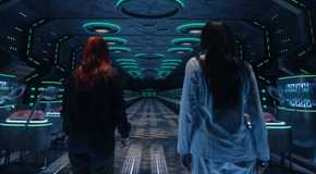Meredith Garretson as Kate Hawthorne standing next to Alice Wetterlund as D'arcy Bloom aboard a spaceship looking at a row of babies in Resident Alien