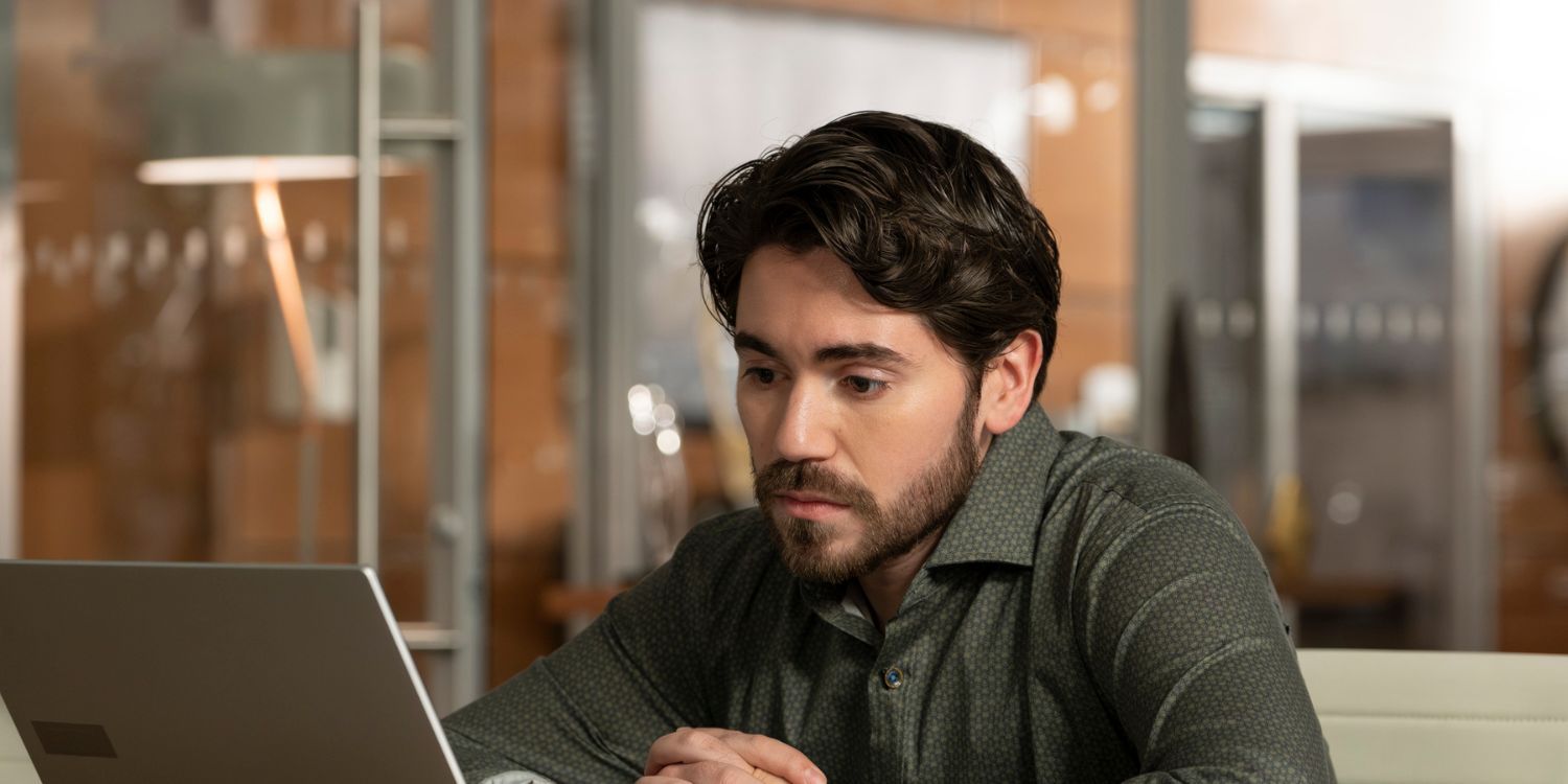 The Good Doctor's Asher sits in the conference room, looking at a computer. He is wearing a green button-down shirt.