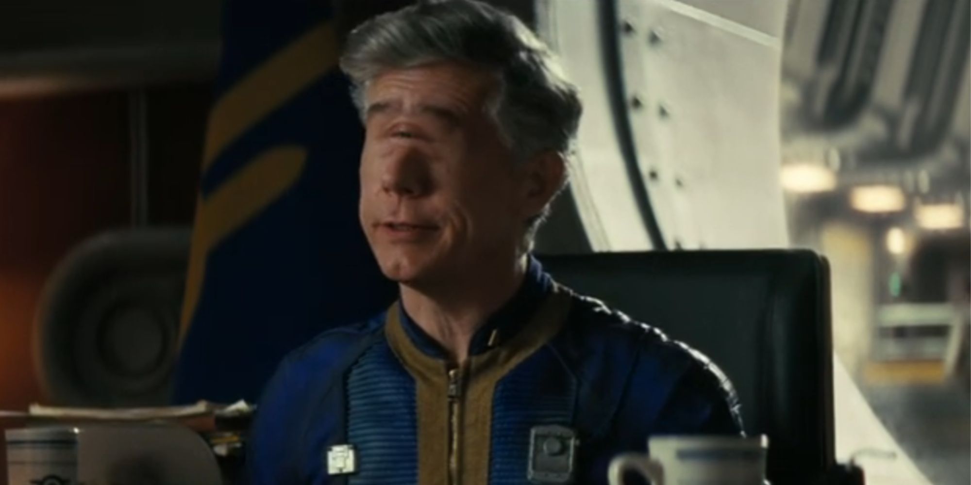 Chris Parnell as Overseer Benjamin in Fallout sitting behind a desk