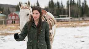 Alisha Newton as Georgie Fleming Morris leading a horse through the snow in Heartland.