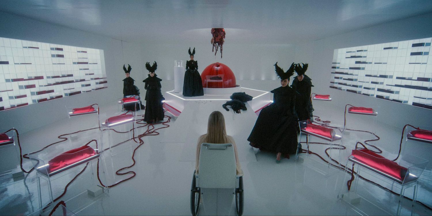 Anna in a wheelchair, meeting with Siobhan and the Delicates in a white room with red details in American Horror Story Delicate season 12 ep 9 (FINALE)