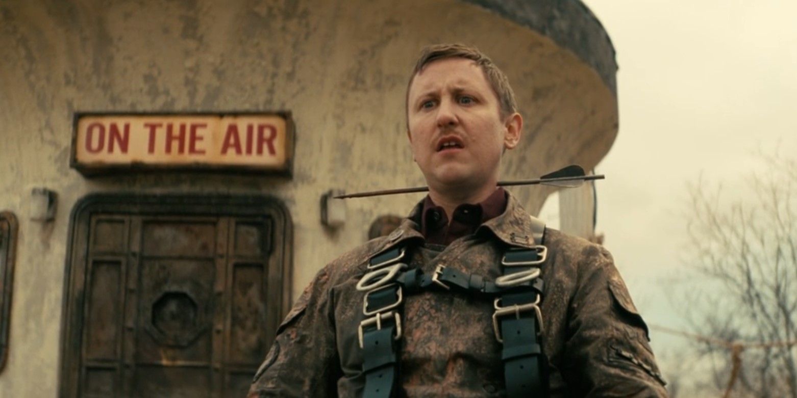Thaddeus (Johnny Pemberton) has an arrow through his neck in front of a sign that reads 