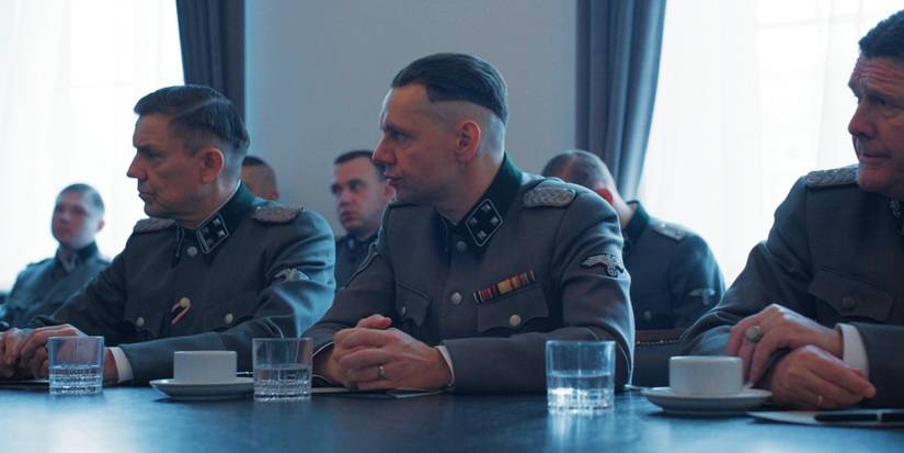 Christian Friedel as Rudolph Hoss sits at a table with other Nazi leaders in The Zone of Interest