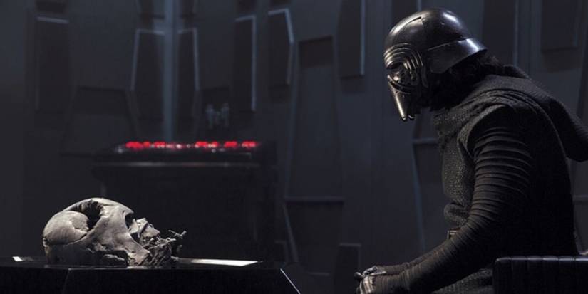 Kylo Ren sitting with Darth Vader's helmet.