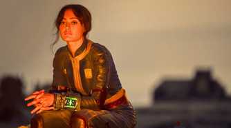 Ella Purnell as Lucy sits by a fire in the Wasteland in Fallout