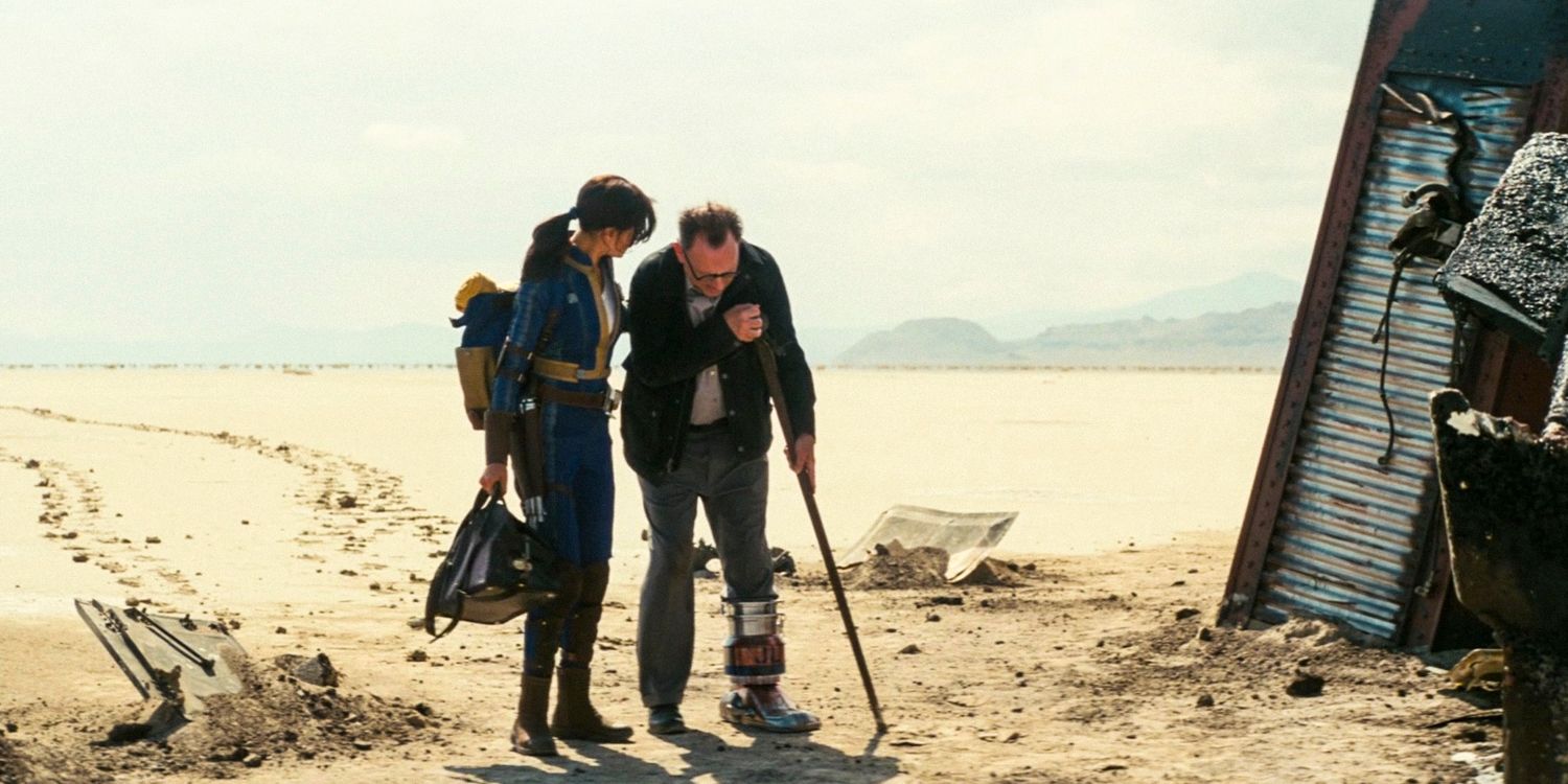 Lucy MacLean in the middle of the desert helps Dr. Siggi Wilzig walk with his new prosthetic foot in Fallout season 1