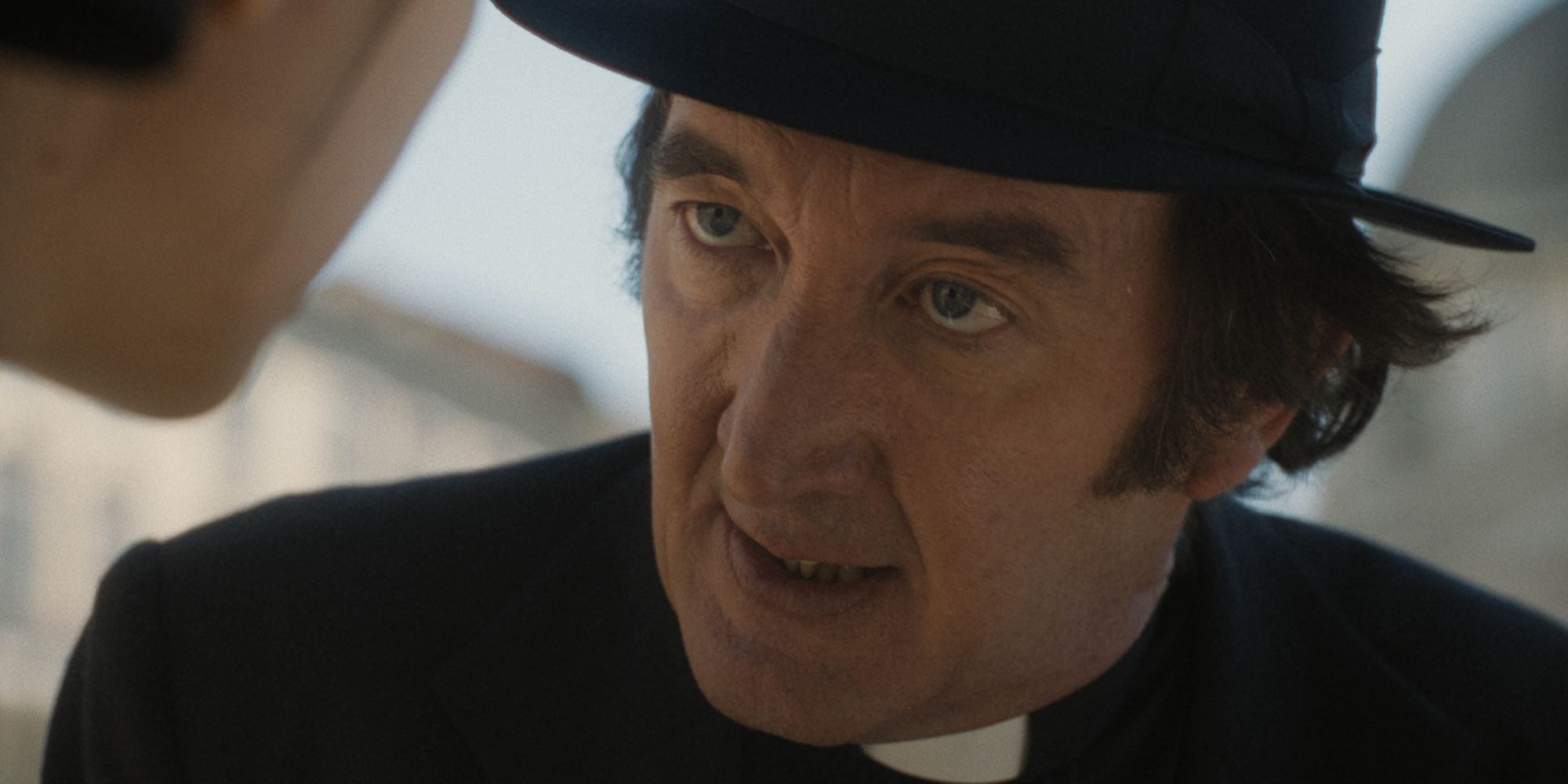 Father Brennan looking stressed while talking to someone in The First Omen movie