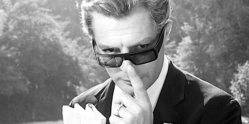Marcello Mastroianni peers mysteriously over his glᴀsses in a scene from 8 1/2