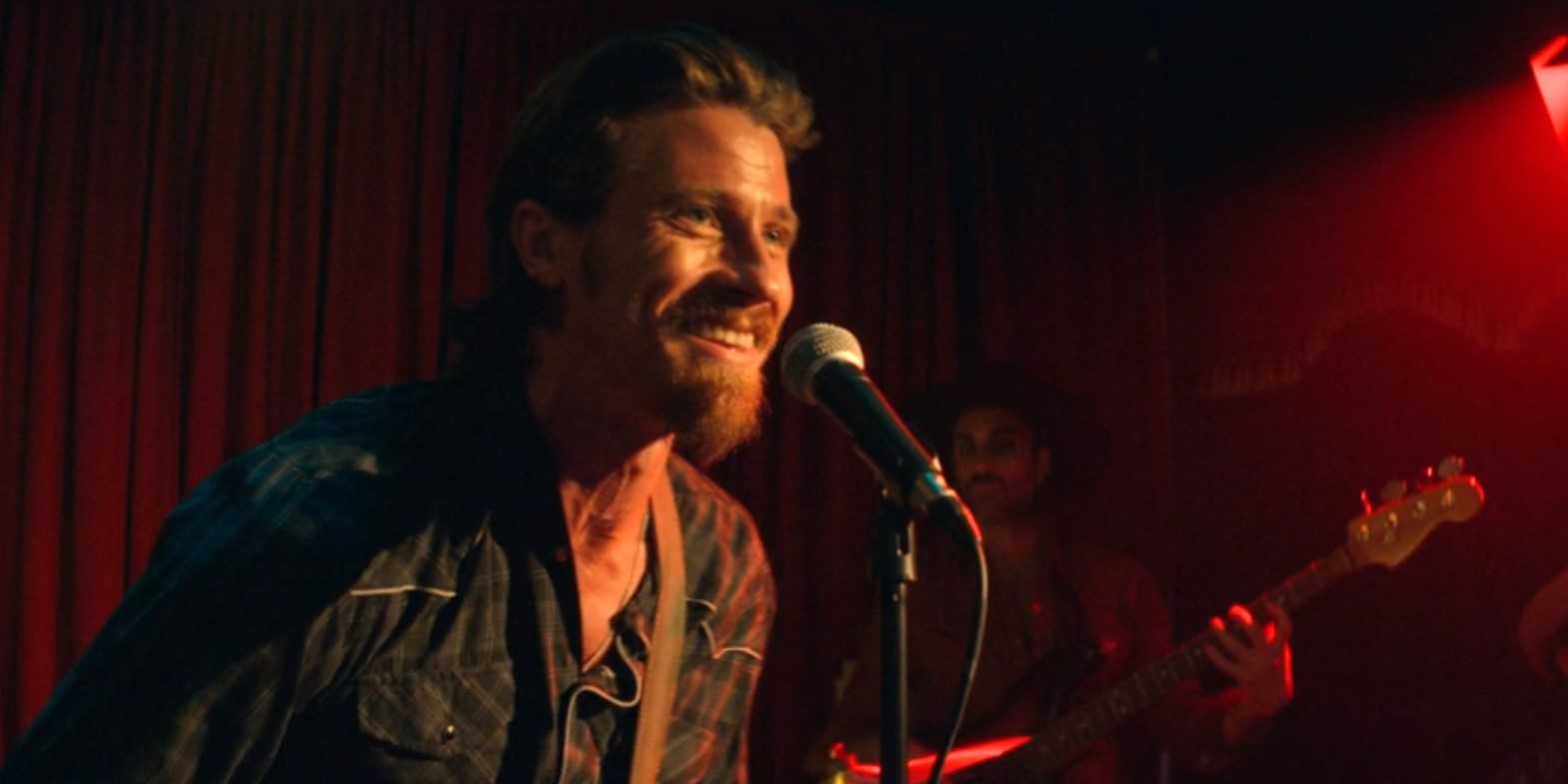 Mitch Keller (Garrett Hedlund) sings into a microphone in Tulsa King