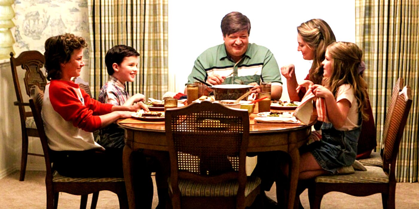 The Coopers sitting around the dinner table and laughing in Young Sheldon