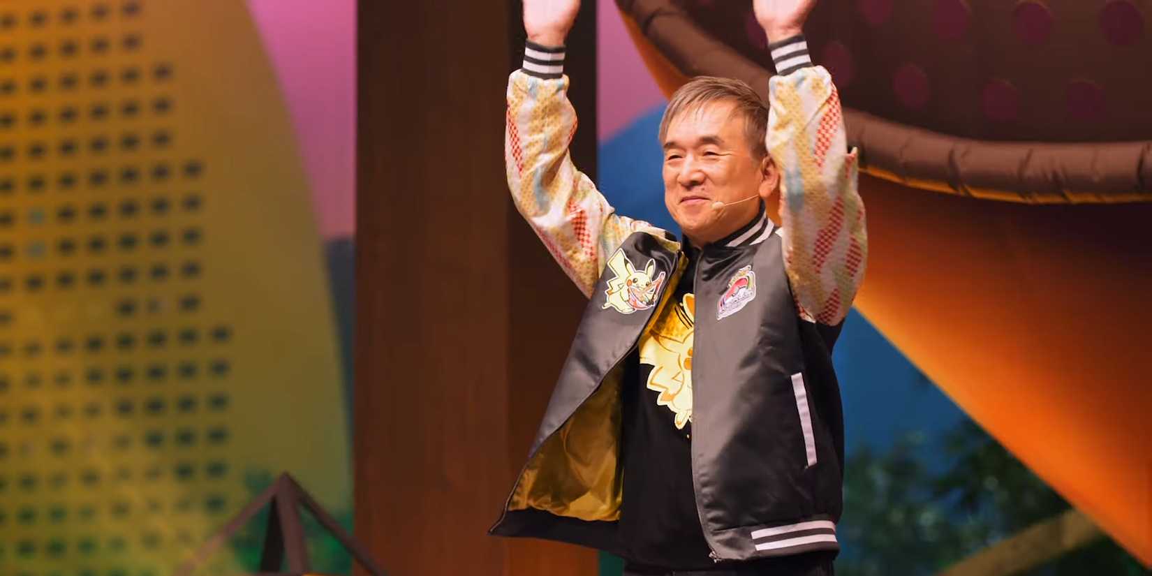Tsunekazu Ishihara raises his arms and smiles at Pokémon Worlds 2023.