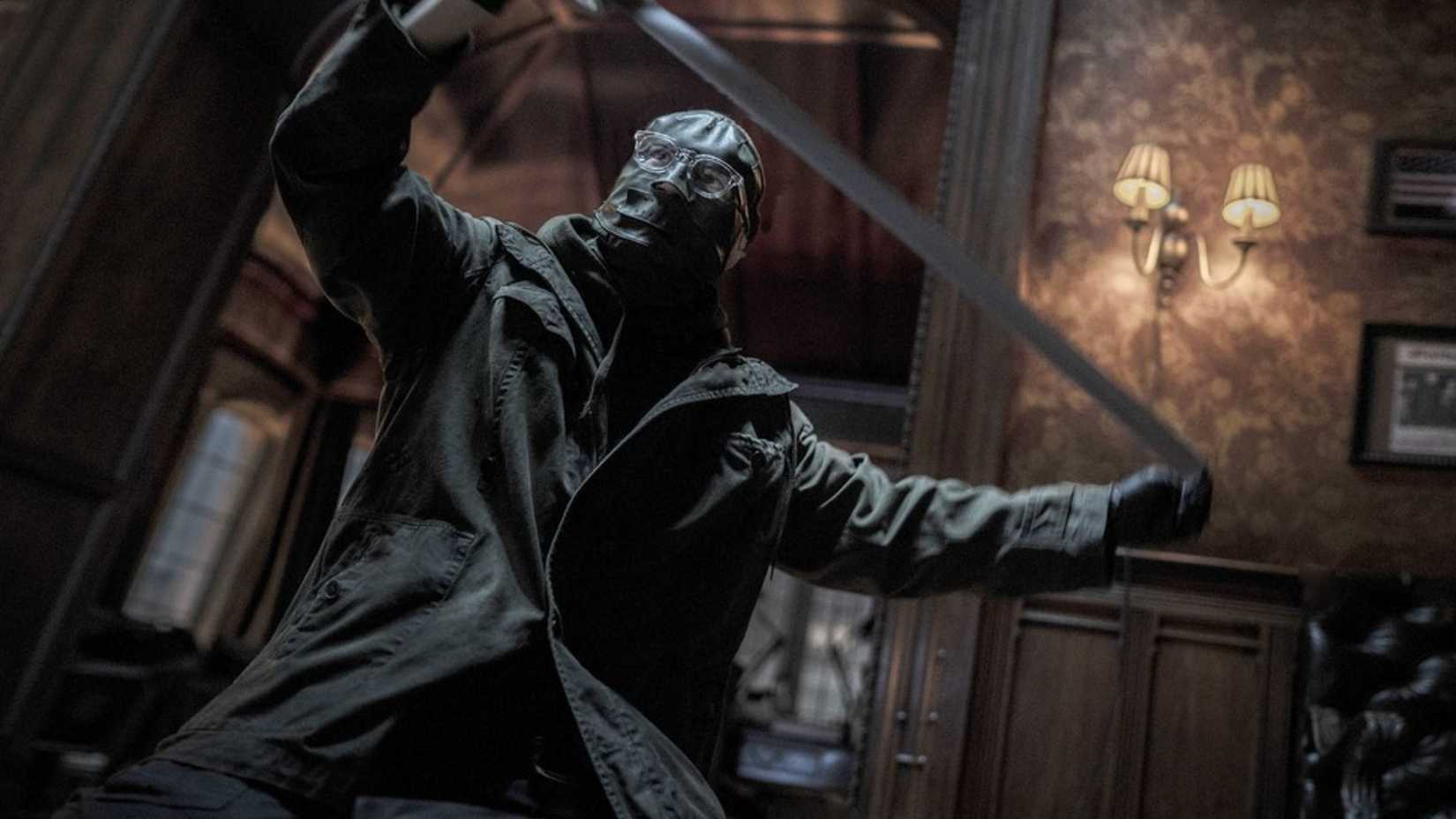O Charada prepara-se para cobrir uma de suas vítimas recém-mortas com fita adesiva em The Batman (2022)