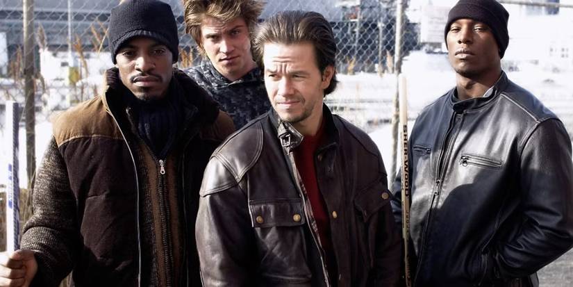 Cena de Quatro Irmãos com Mark Wahlberg e elenco em frente a uma cerca de arame