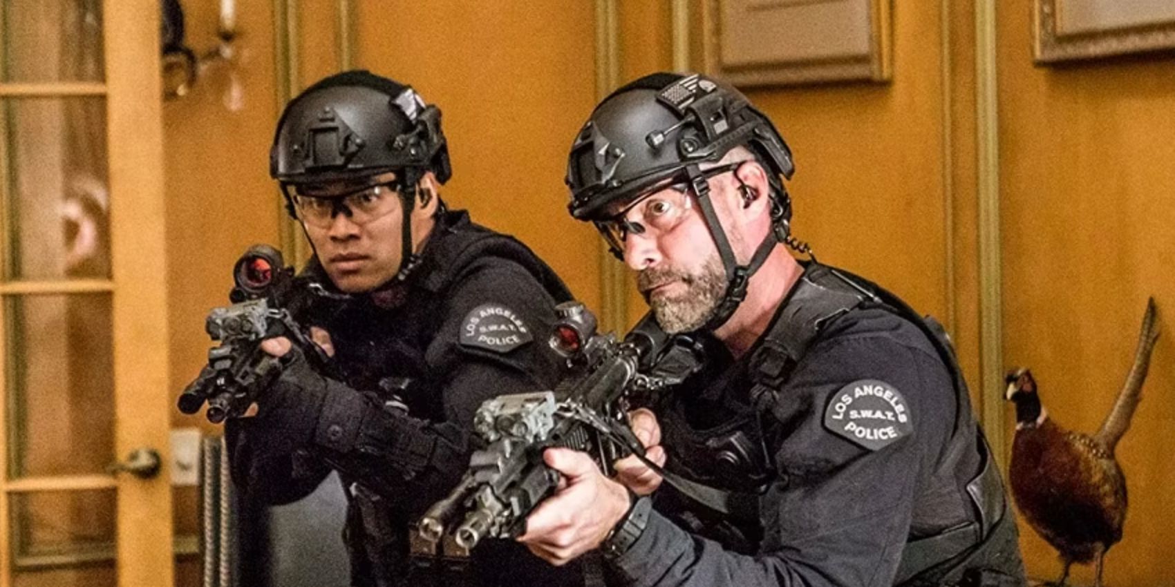 Tan and Deacon in uniform with their guns drawn inside a house in the SWAT episode Invisible