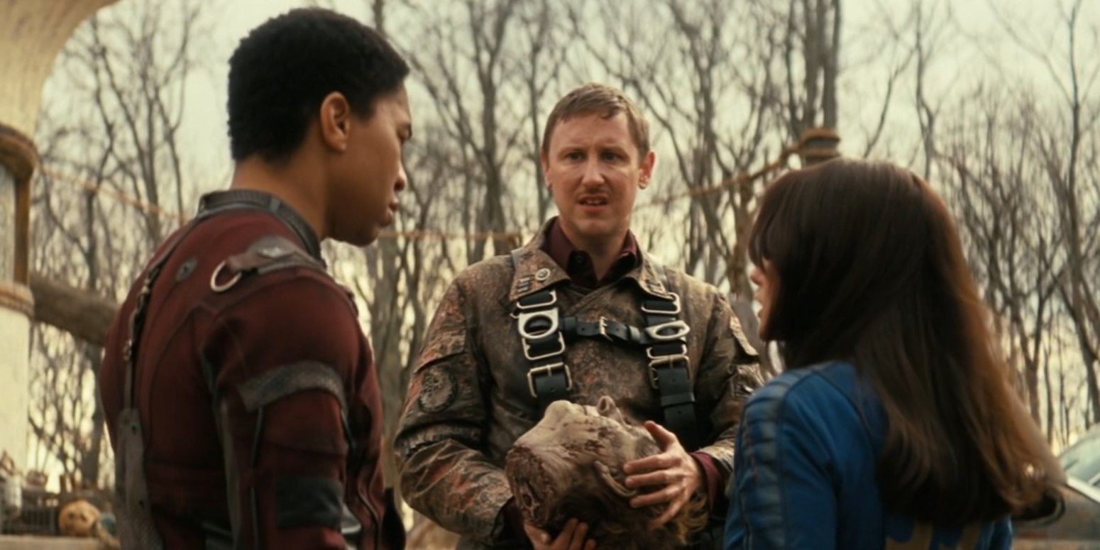 Maximus, Thaddeus, and Lucy stand talking in a circle while Thaddeus holds Siggi's head in Fallout