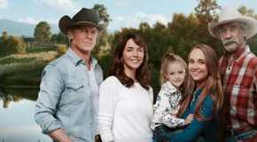 The main cast of Heartland season 16 posing and smiling in front of the ranch.