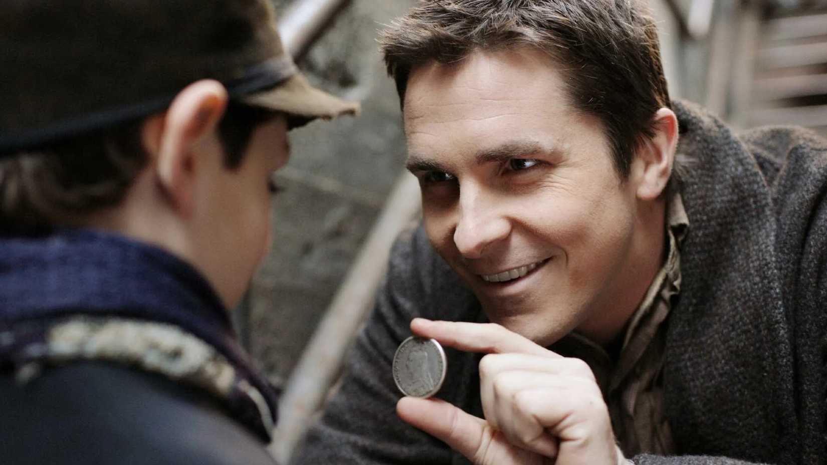 Christian Bale holding up a coin in The Prestige