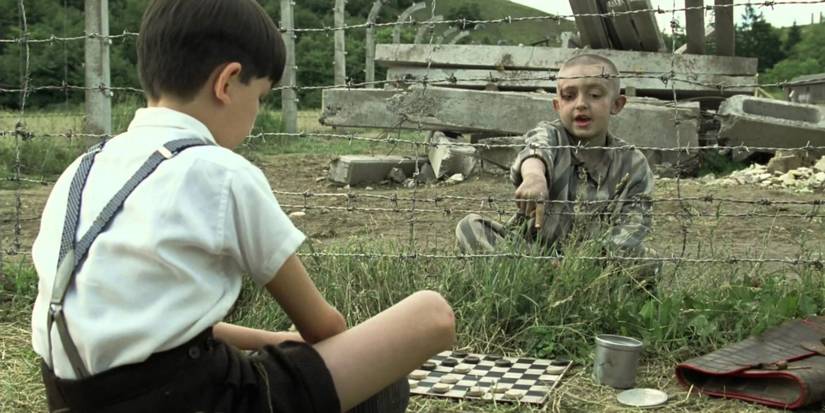 10 Movies Too Upsetting To Watch A Second Time 4 Two boys play checkers on opposite sides of a fence in The Boy in the Striped Pajamas