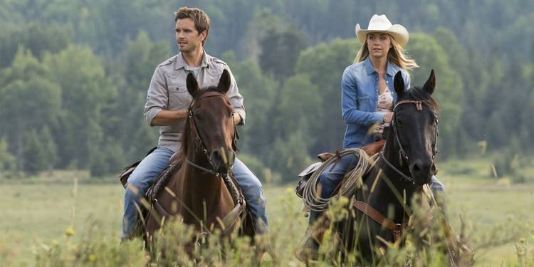 Ty (Graham Wardle) and Amy Fleming (Amber Marshall) riding horses and laughing in Heartland.
