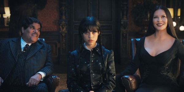 Luis Guzmán as Gomez Addams with Jenna Ortega as Wednesday Addams and Catherine Zeta-Jones as Morticia Addams sitting in Wednesday