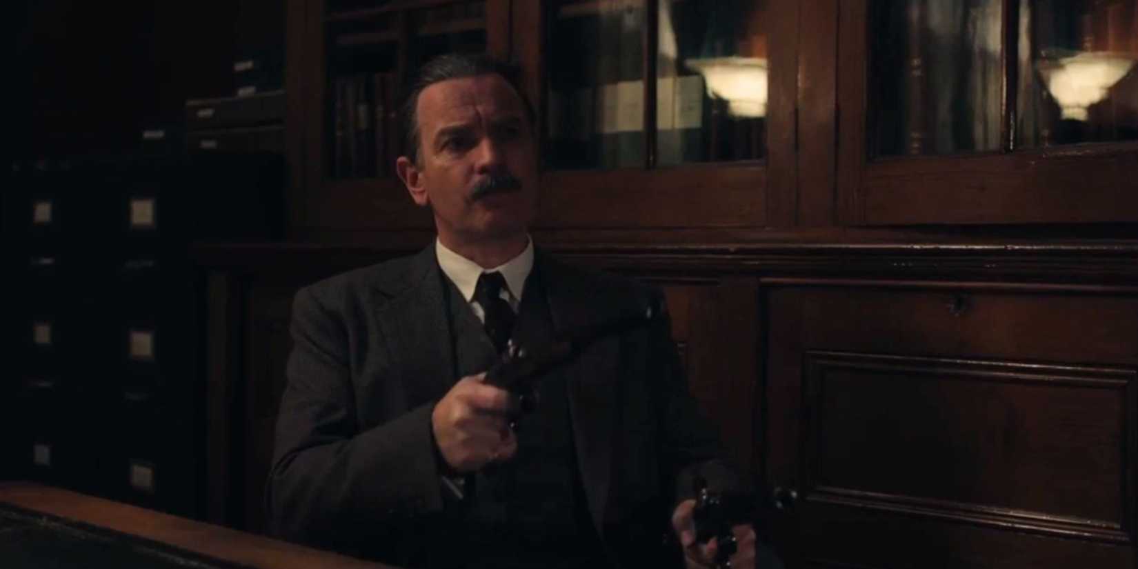 Ewan McGregor as Alexander Rostov aiming a gun at someone off-screen in A Gentleman in Moscow