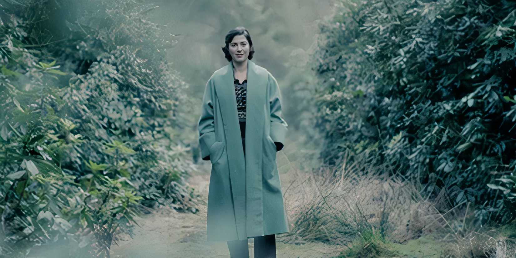 Mary Elizabeth Winstead in a long coat standing between two bushes as Anna Urbanova in A Gentleman in Moscow
