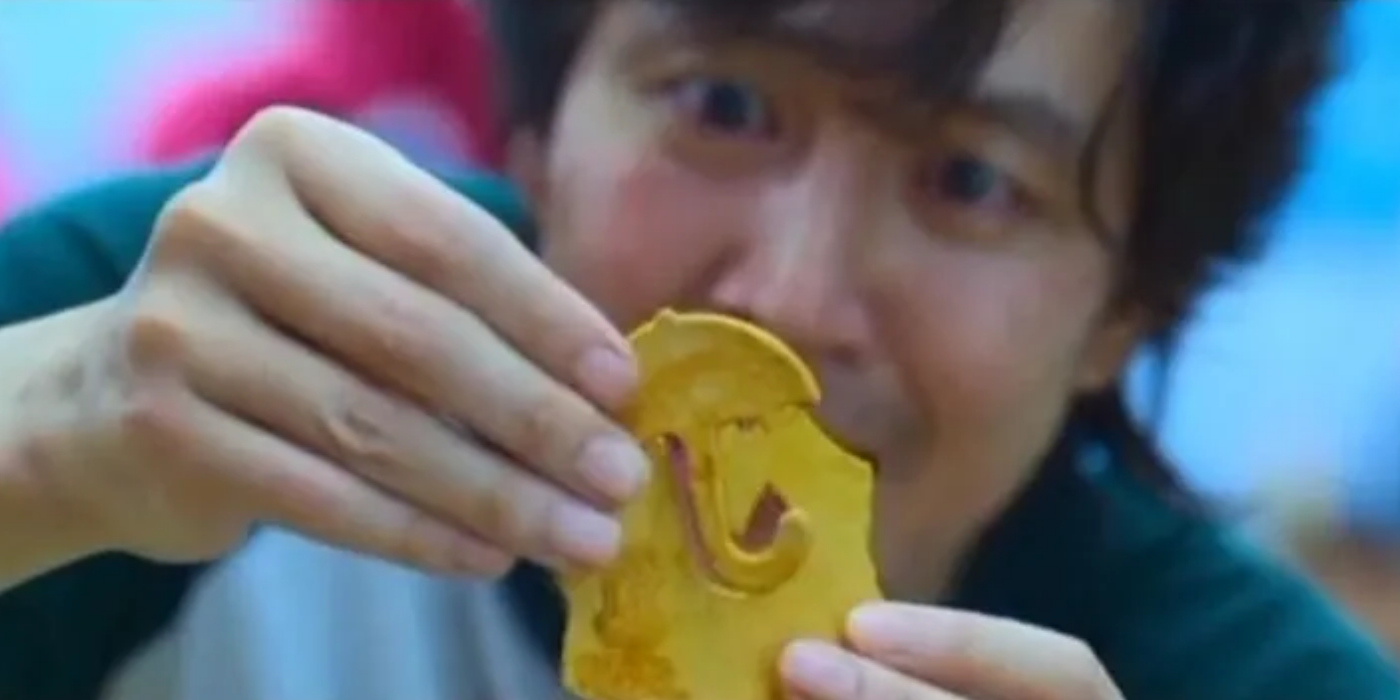 A contestant holding a piece of hardened honeycomb in Squid Game