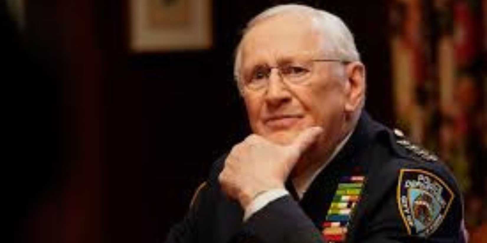 Henry Reagan sitting at a table wearing a police uniform in Blue Bloods
