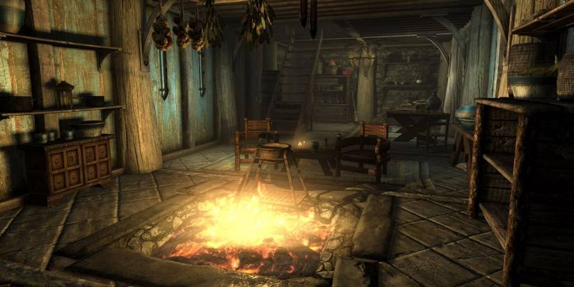 Skyrim Decorated Breezehome Interior With Glowing Fire Pit And Cooking Pot, Table And Chairs And Ingredients Hanging From Ceiling