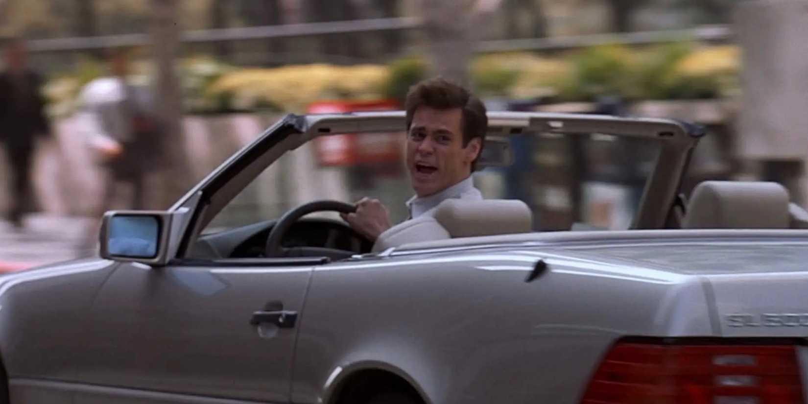 Jim Carrey is yelling and looking back as he's driving. 