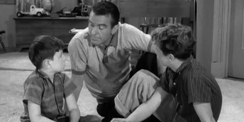 Ward sitting on the floor and talking to Beaver and Wally.