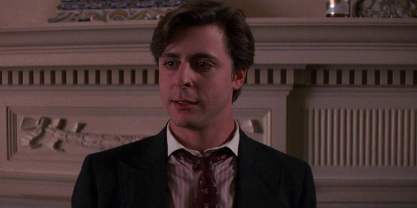 Дж. Нэлсон выглядит напряженным в костюме перед вырезанной белой стеной в фильме "Огонь в Эльме"