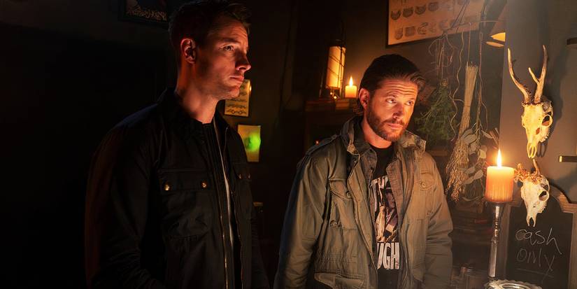 Justin Hartley as Colter Shaw and Jensen Ackles as Russell Shaw standing together in a candlelit room in Tracker
