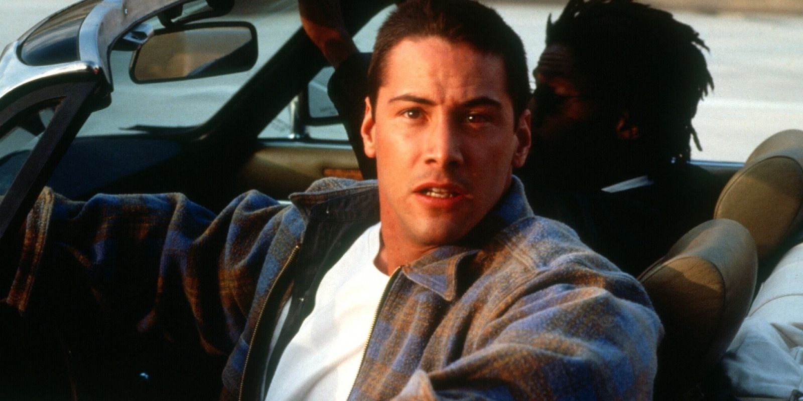 Keanu Reeves as Jack Traven looking concerned while driving a car in Speed