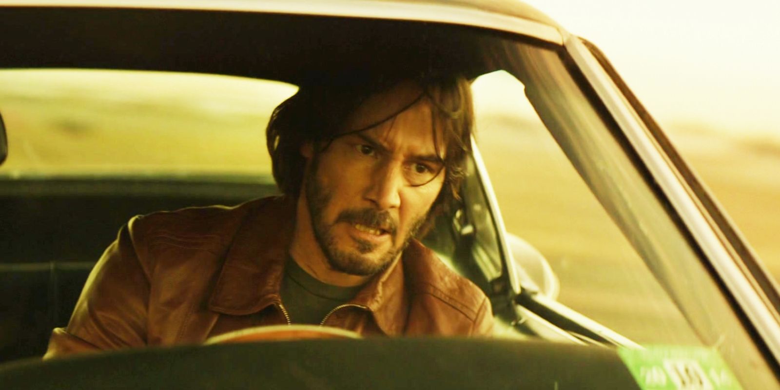 Keanu Reeves driving and looking angry in John Wick