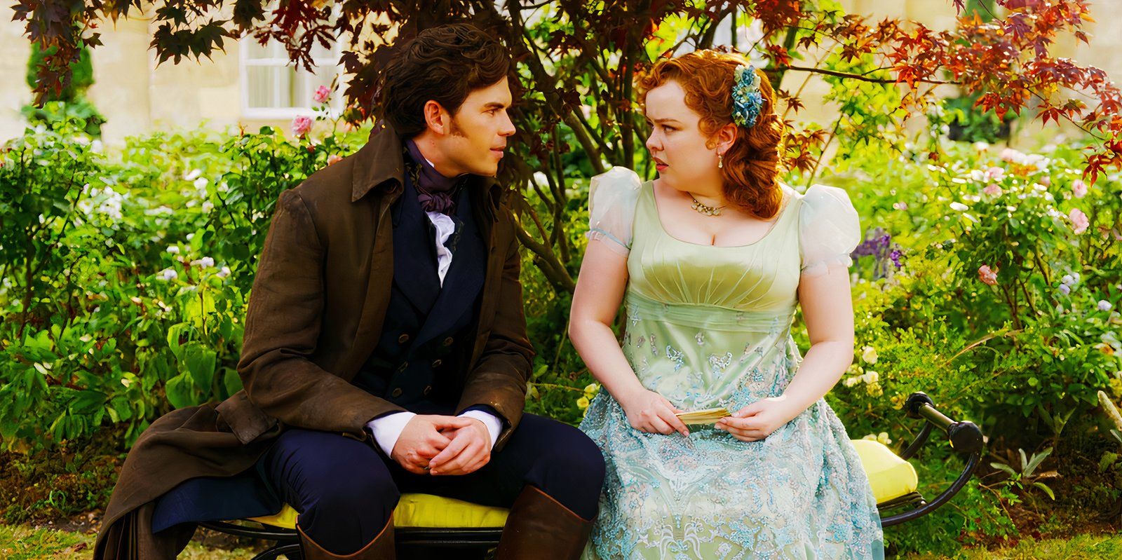 Luke Newton as Colin Bridgerton and Nicola Coughlan as Penelope Featherington Sitting on a Bench in Bridgerton season 3 episode 1