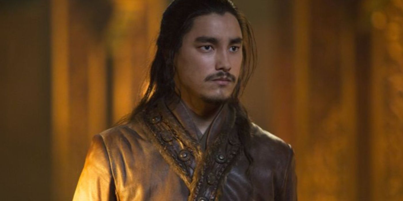 Remy Hii as Jingim in a robe and looking serious in Marco Polo