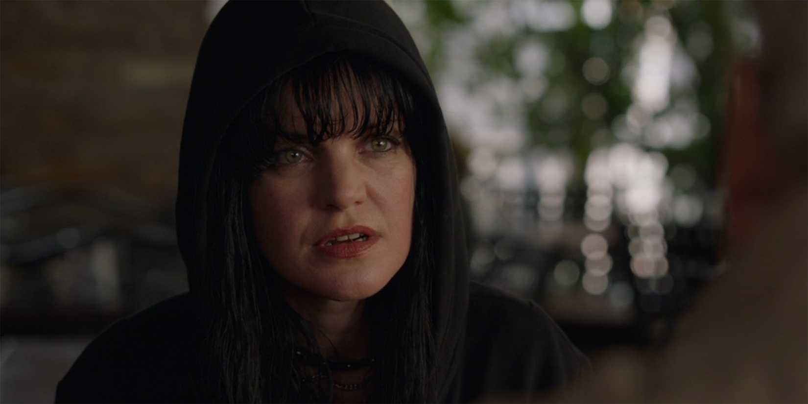 A close up of Abby Sciuto wearing a black hood and looking concerned in NCIS
