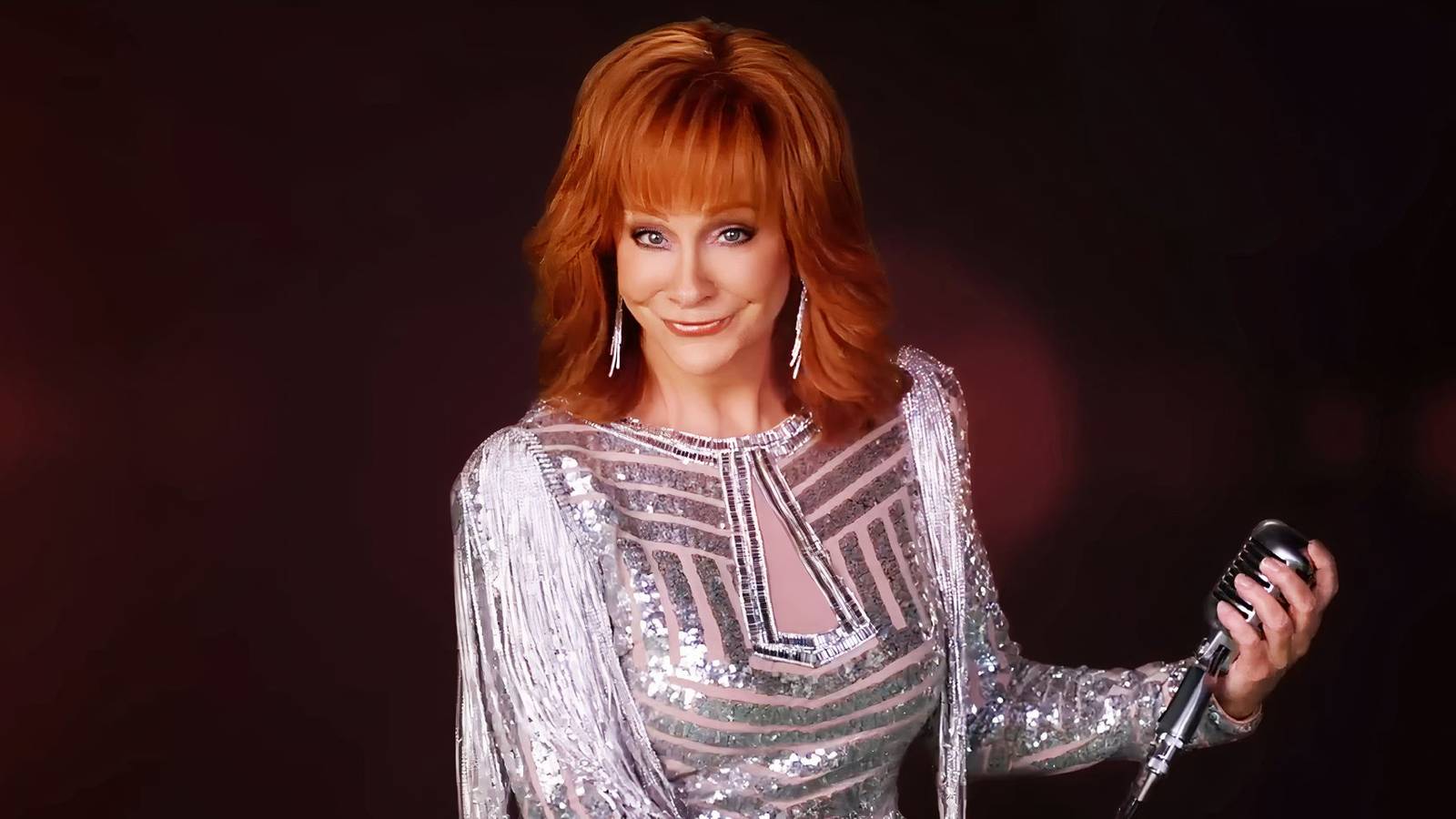 Reba with a microphone in the trailer for Happy's Place