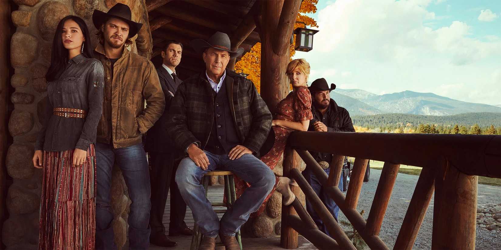 The cast of Yellowstone posing on the porch of the Dutton ranch house.