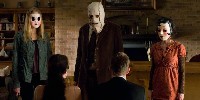 Três assassinos mascarados decidem o que fazer com suas vítimas em The Strangers