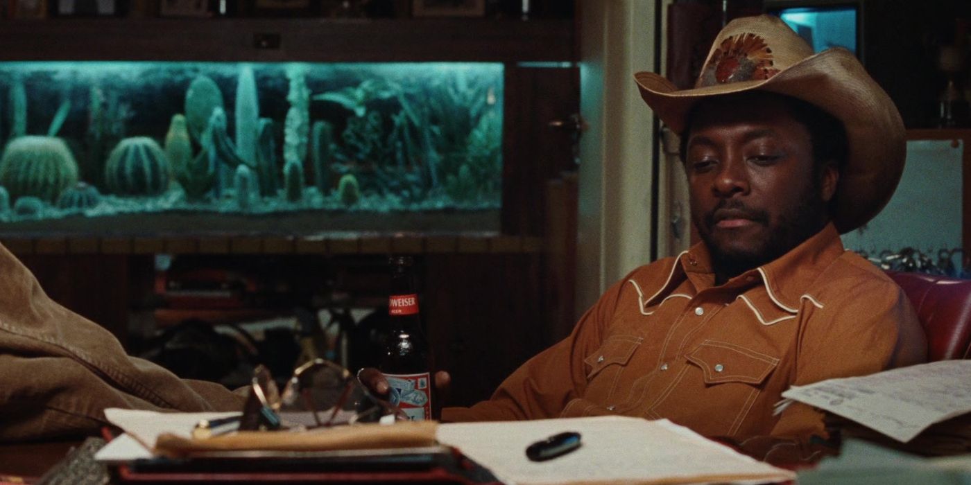 Will.i.am as John Wraith sitting with his feet on a desk in X-Men Origins: Wolverine (2009)