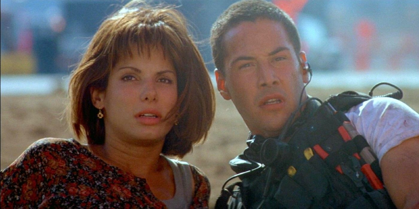 Keanu Reeves and Sandra Bullock on the ground and looking off in the distance in Speed