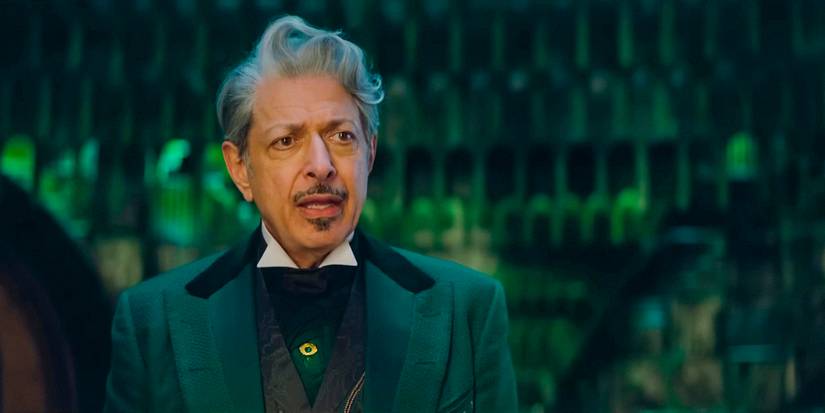 Jeff Goldblum as The Wizard looks dismayed as he stares across the room, getting emotional, in Wicked.